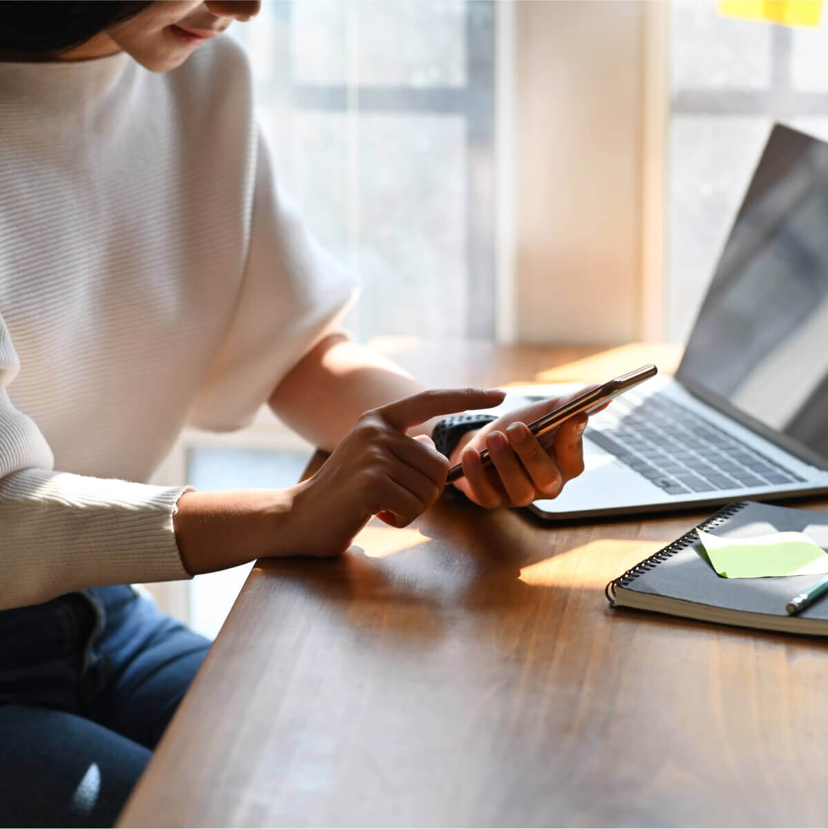 Cyber safety online promotion image of person holding a phone near a laptop computer